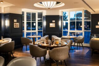 Elegantes Restaurant mit stilvollen Tischen und Fenstern, die auf die Straße blicken.
