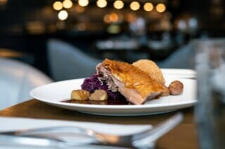 Knusprige Ente mit Rotkohl, Kartoffeln und einer Beilage auf elegantem Teller.