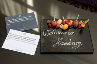 Hotel Atlantic Willkommensgruß in Hamburg mit Süßigkeiten und inspirierenden Zitaten auf einem Tisch.
