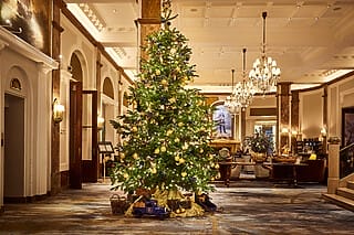 Weihnachtsbaum im eleganten Hotel-Lobby, festlich geschmückt mit Lichtern und Ornamenten.