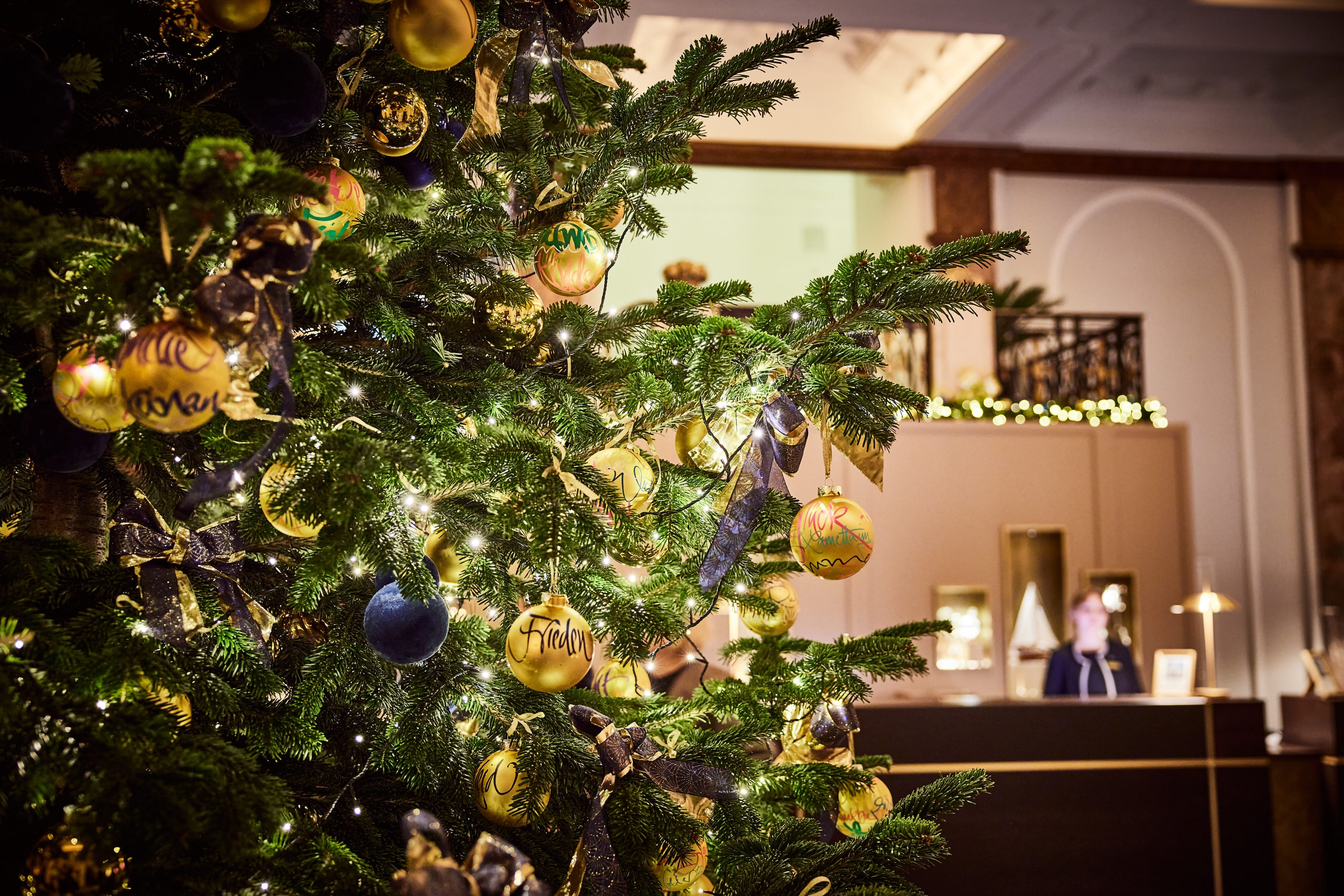 Hotel Atlantic Weihnachtsbaum mit goldenen und blauen Kugeln, Lichtern und festlicher Dekoration im Hintergrund.