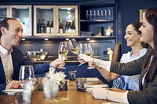 Hotel Atlantic Freunde stoßen in einem eleganten Restaurant mit Weißwein an und genießen die gemeinsame Zeit.