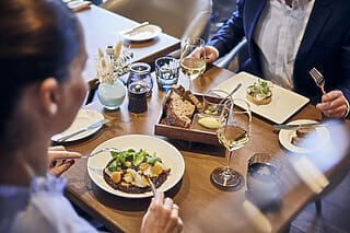 Elegantes Restaurant mit zwei Gästen, die feines Essen und Wein genießen.