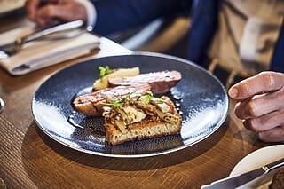Gourmetgericht auf einem Teller: Brot mit Zwiebeln, Fleisch und Beilagen, elegant serviert.