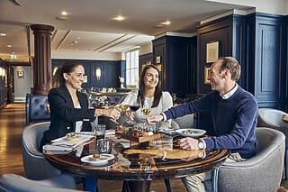 Freunde stoßen an einem eleganten Tisch mit Wein und köstlichem Essen in einem Restaurant an.