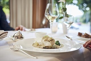 Gourmetgericht mit Fisch, Gemüse und Soße, serviert in elegantem Restaurant-Ambiente.