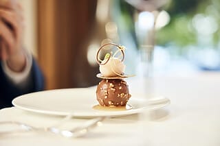 Chocolate dessert with ice cream, caramel sauce and decorative garnish on a white plate.