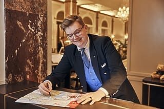 Hotel Atlantic Hotelmitarbeiter zeichnet auf einer Karte, um Gästen hilfreiche Informationen zu bieten.