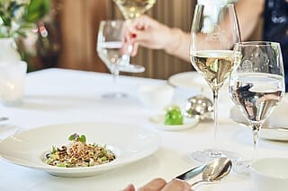 Elegant table setting with fine food, wine and water in a restaurant ambience.