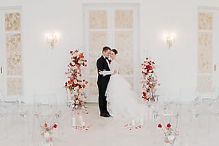 Brautpaar in eleganter Hochzeitszeremonie vor blumiger Kulisse und Kerzen.