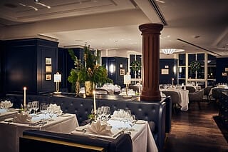 Elegantes Restaurant mit festlicher Tischdekoration und stilvollem Ambiente bei Nacht.