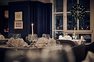 Elegant gedeckter Tisch im Restaurant mit Kerze, Gläsern und festlicher Dekoration.