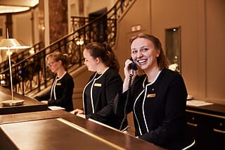 Freundliches Hotelpersonal an der Rezeption, das Gäste am Telefon betreut.