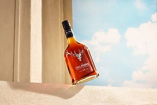 Flasche Dalmore 18 Jahre Whisky auf einem hellen Hintergrund mit Wolken.