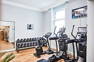 Modern fitness studio with cardio equipment, weights and large mirror. Bright, inviting room.