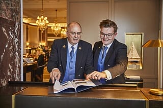 Zwei Hotelmitarbeiter besprechen ein Buch am Empfang in einem eleganten Hotel.