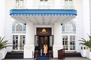 Entrance to the Hotel Atlantic in Hamburg with elegant façade and green palm trees.